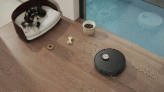 Robot vacuum cleaning a wooden floor near a dog bed