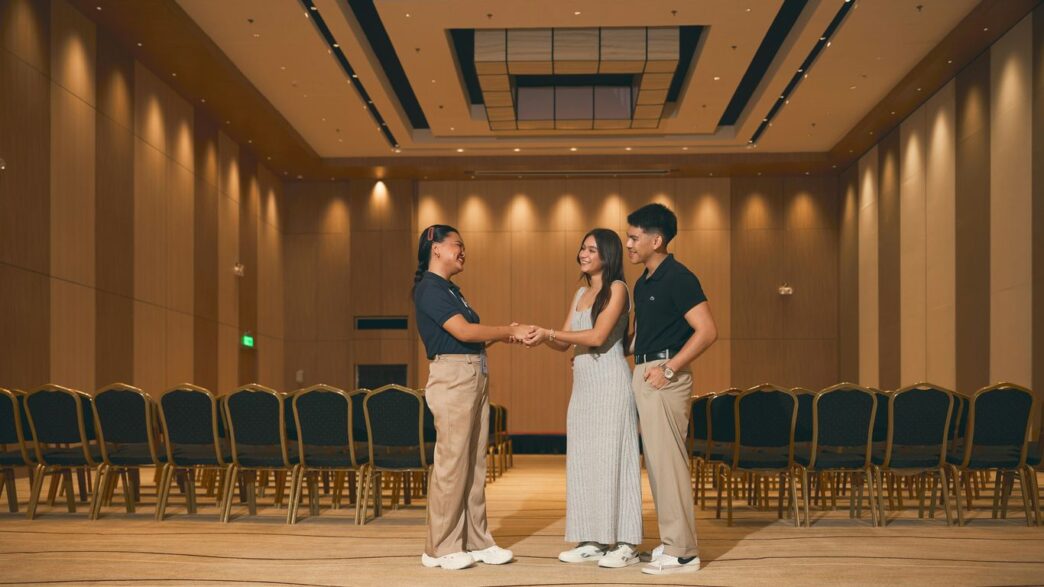 Three people standing in an empty conference room.