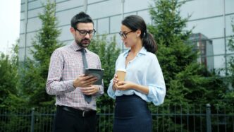 Two professionals discussing a tablet outside office building