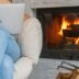 a woman sitting in a chair with a laptop in front of a fireplace