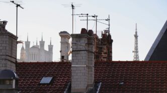 Rooftops and chimneys with distant cityscape and tower.