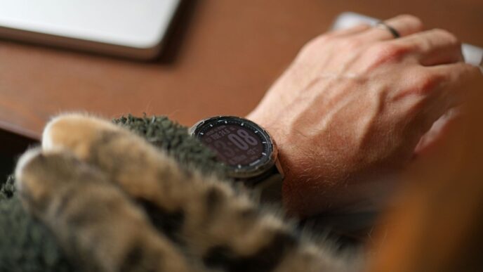 A hand working while a cat snuggles.