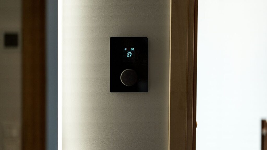 A modern black thermostat mounted on a wall.