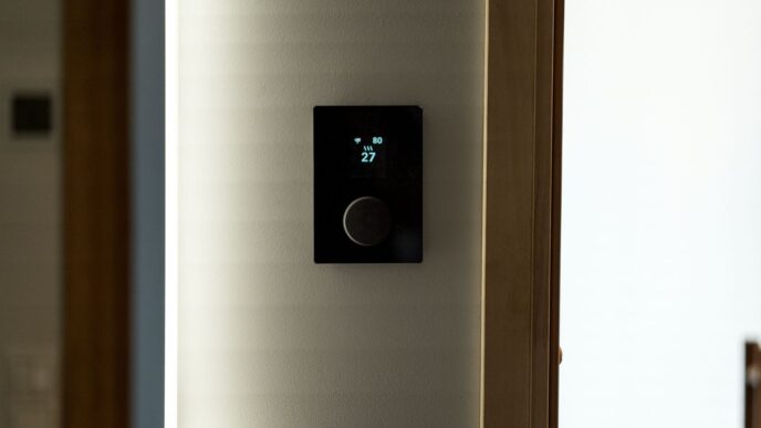 A modern black thermostat mounted on a wall.