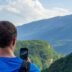 A man taking a picture of mountains with his cell phone