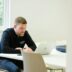 Man working on laptop at a white table.