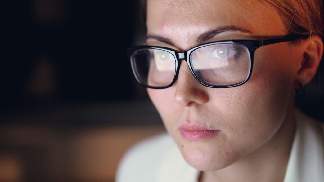 Woman wearing glasses looking intently at screen