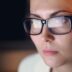 Woman wearing glasses looking intently at screen