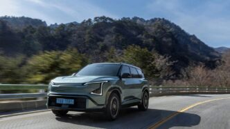 A light green suv drives on a winding road.