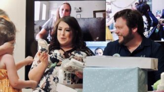 woman in white and black floral shirt holding white box