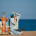 a person sitting on a beach with a suitcase and a laptop