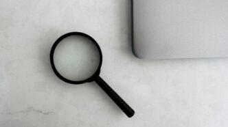 Magnifying glass sits near a laptop on a table.
