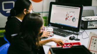 a couple of women sitting at a table with a laptop