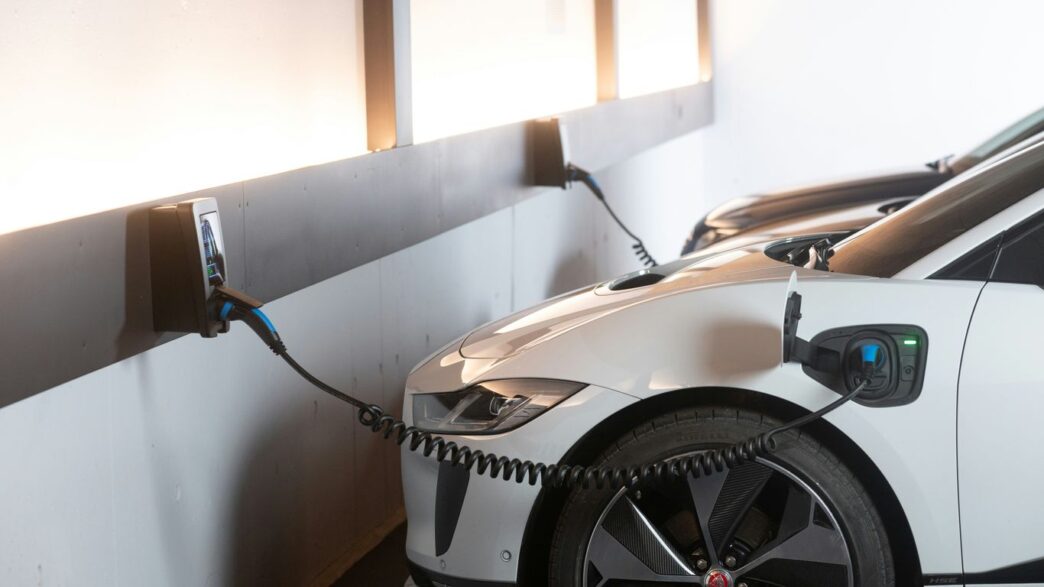 White electric car charging at a station.