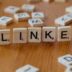 A wooden table topped with scrabble tiles spelling the word link
