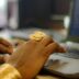 Hands typing on a laptop with gold jewelry