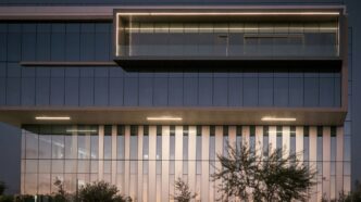 Modern office building exterior at dusk with lights.