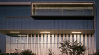 Modern office building exterior at dusk with lights.