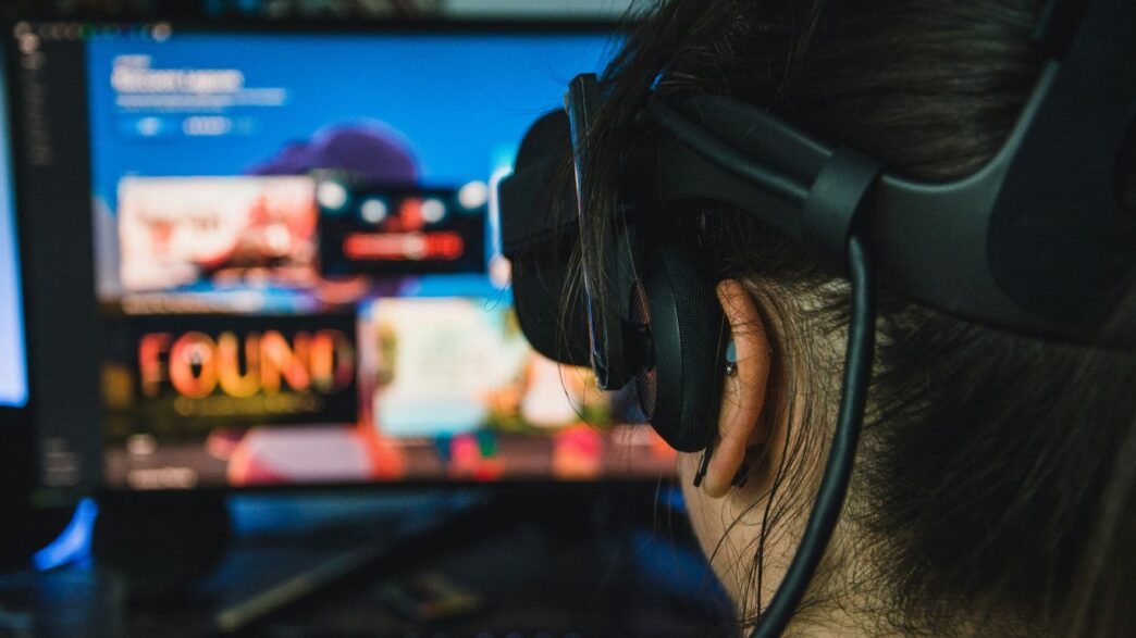 person wearing black headphones in front of black flat screen computer monitor