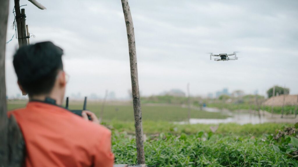man in orange shirt standing near green grass field during daytime