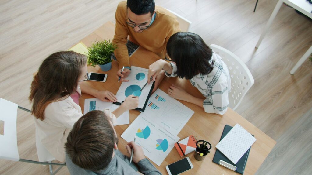 Team collaborating around a table with charts.