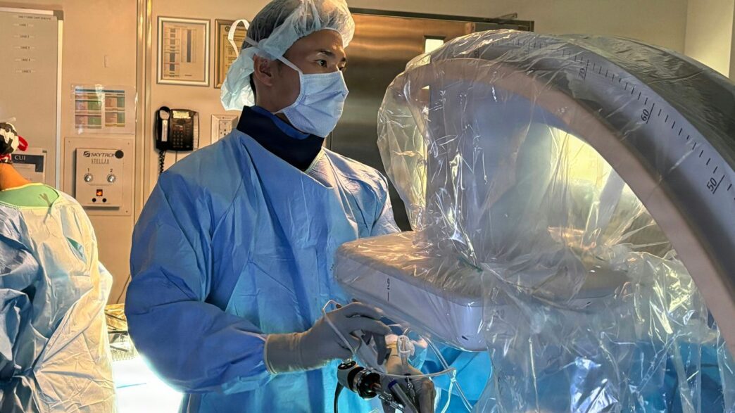 Surgeon in mask operating robotic surgical equipment in operating room