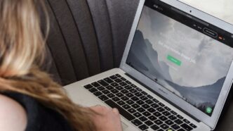 person using macbook air on gray couch